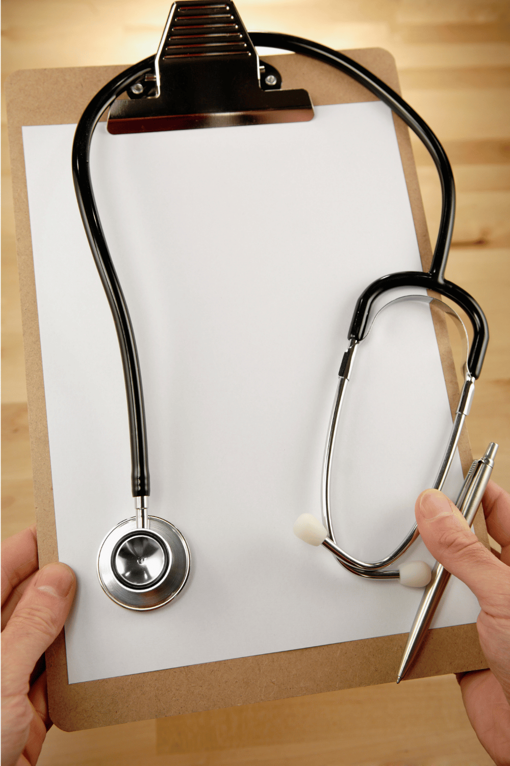 stethoscope on clipboard held in hands with pen