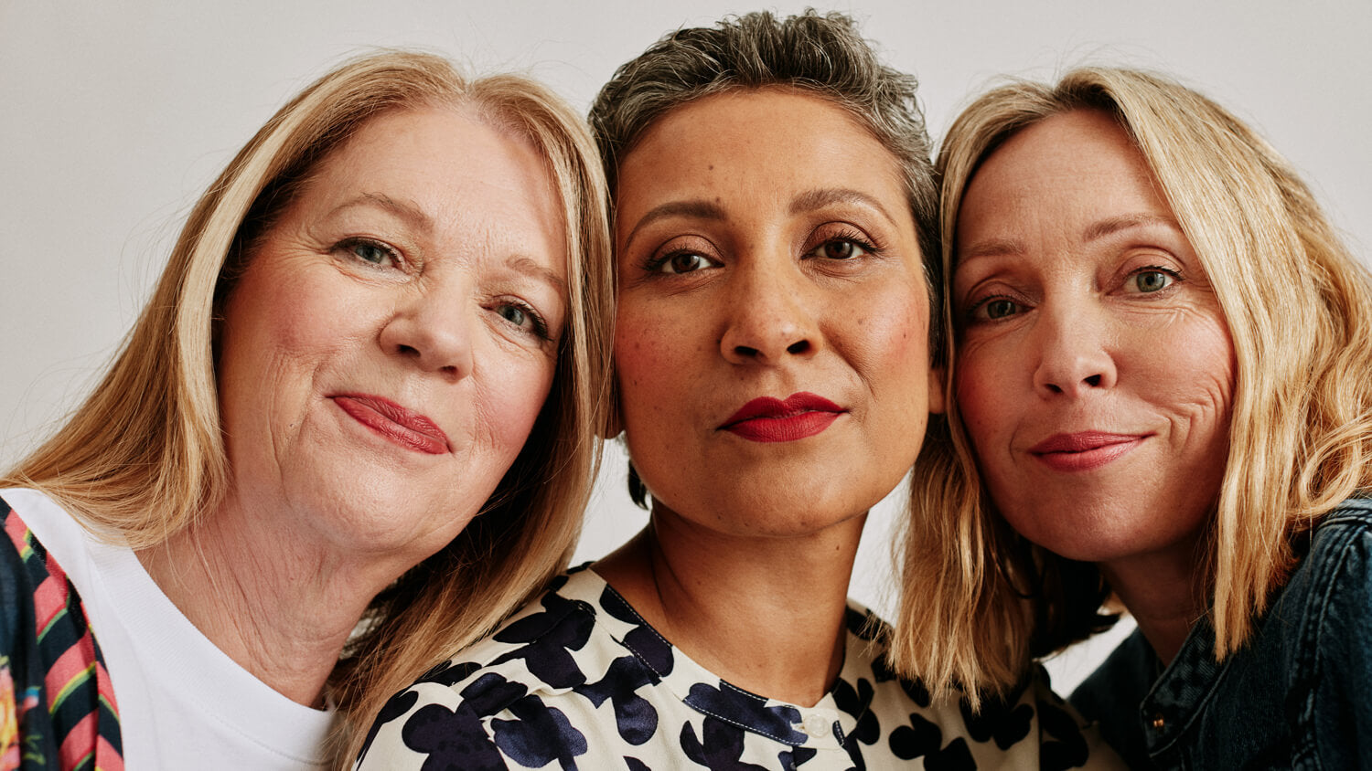 Three women leading their heads together while smiling