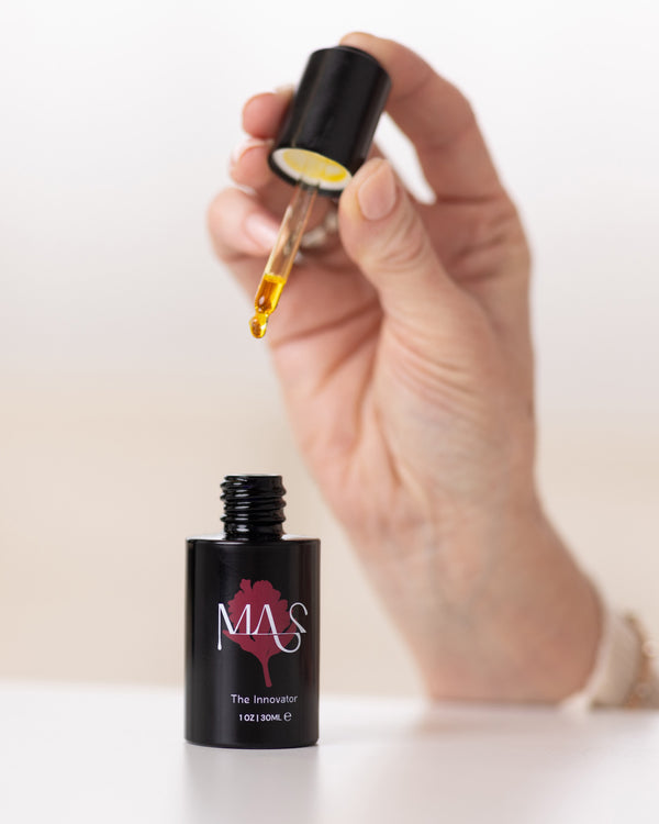 A hand holding The Lunaescent Bundle skin oil dropper